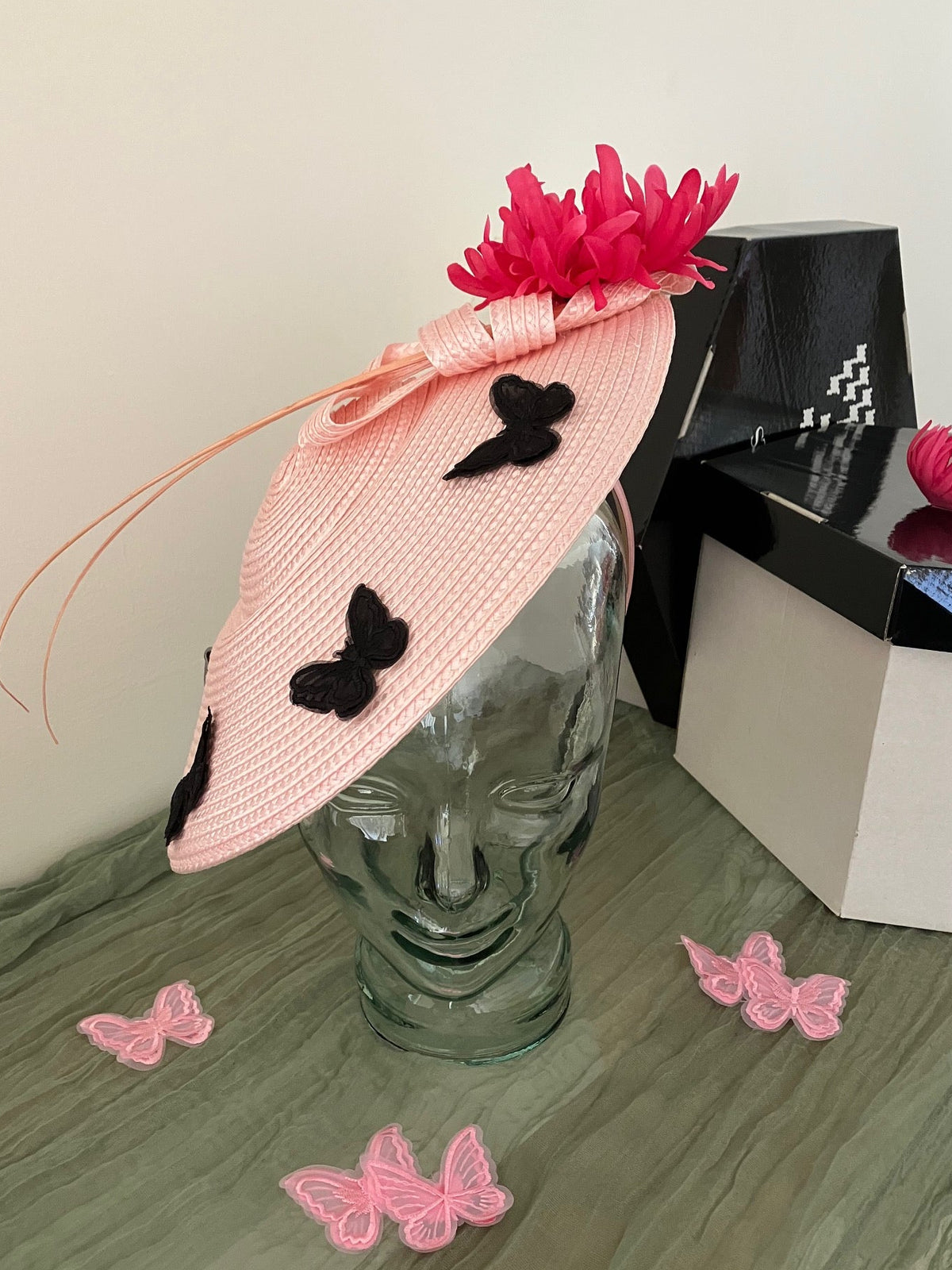 Ladies light pink woven fascinator hat with black butterfly appliqués and a bright pink feather flower