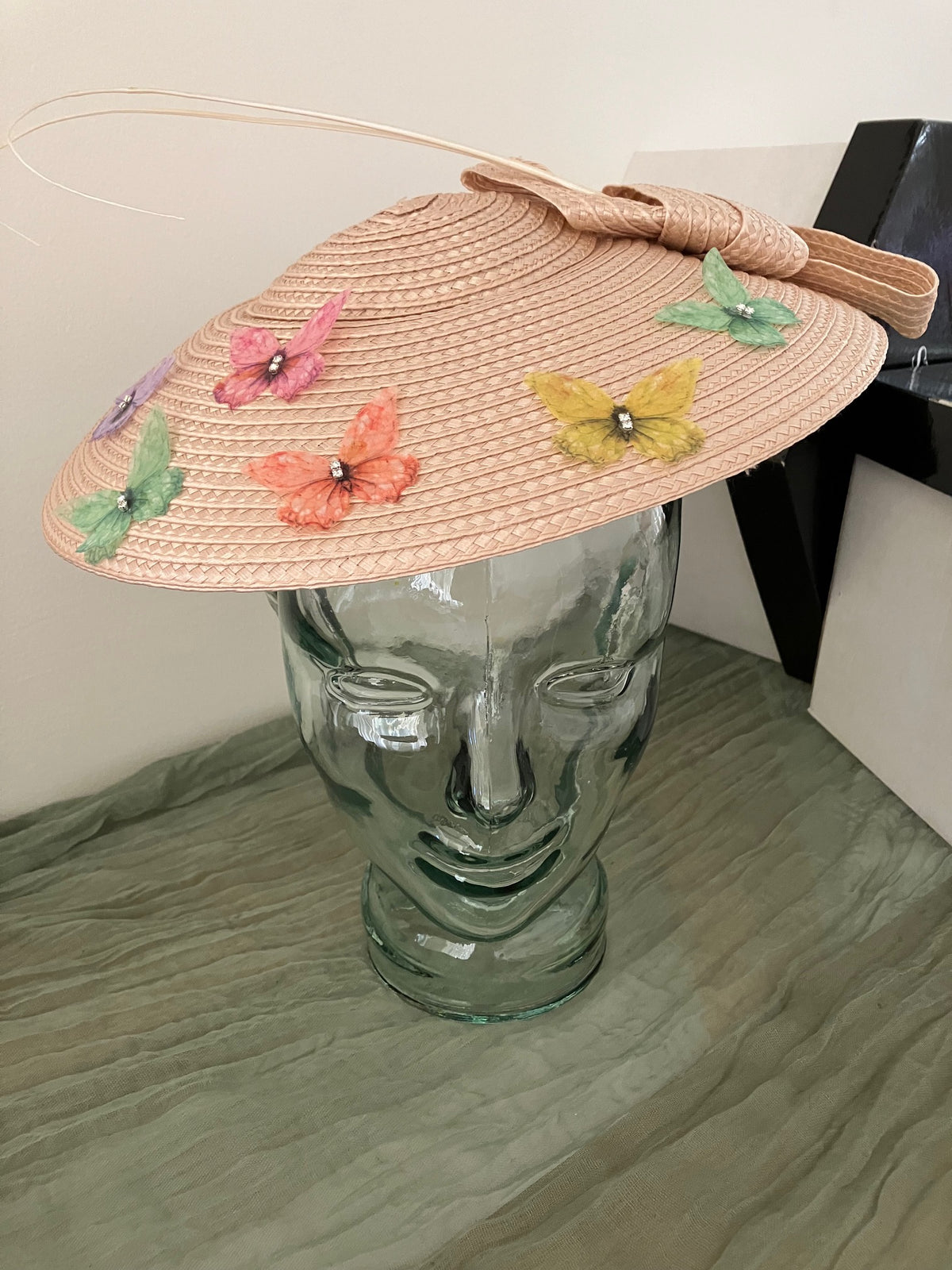 Ladies lightweight fascinator in a light peach-beige color with colorful fabric butterfies.