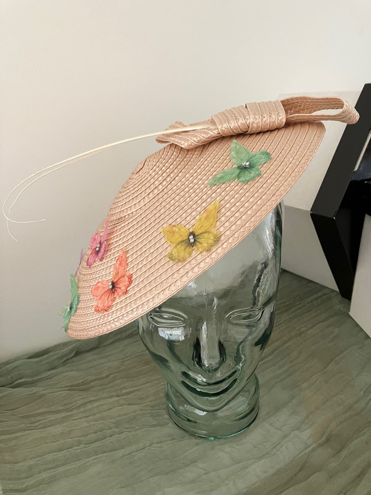 Ladies lightweight fascinator in a light peach-beige color with colorful fabric butterfies.