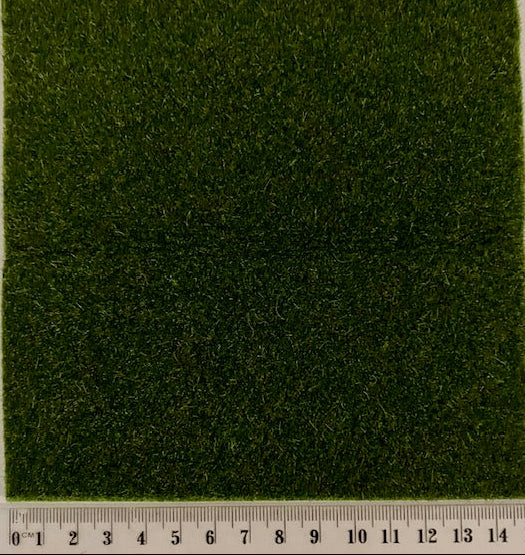 A square sample of green artificial grass or turf texture with a ruler along the bottom edge showing measurements in centimeters.
