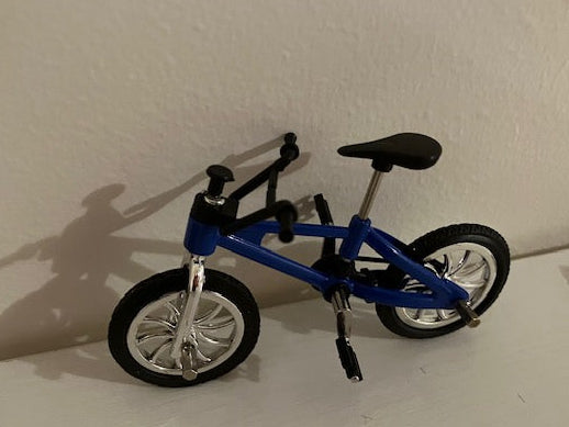 A miniature blue bicycle with black tyres, a black seat, and silver-colored rims.