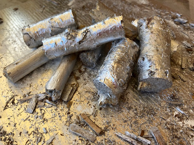 Several natural wood cylindrical logs or stakes with rough bark and cut ends.